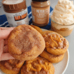 Pumpkin cookies stacked on a tray dusted with cinnamon sugar
