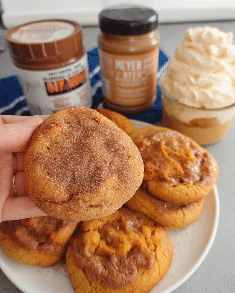 Pumpkin cookies stacked on a tray dusted with cinnamon sugar