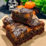Spooky Halloween cream cheese swirl brownies recipe! These decadent dark chocolate brownies are topped with a layer of orange cheesecake swirled together for a festive treat. Get the recipe and bake a batch for your Halloween party!