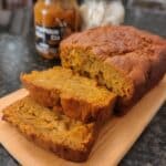 Sliced pumpkin bread on wooden cutting board with fall decor