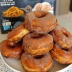 Pumpkin donuts coated in cinnamon sugar on wire rack