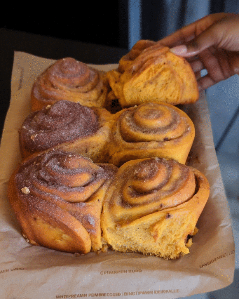Unbaked pumpkin spice cinnamon rolls in parchment-lined baking pan