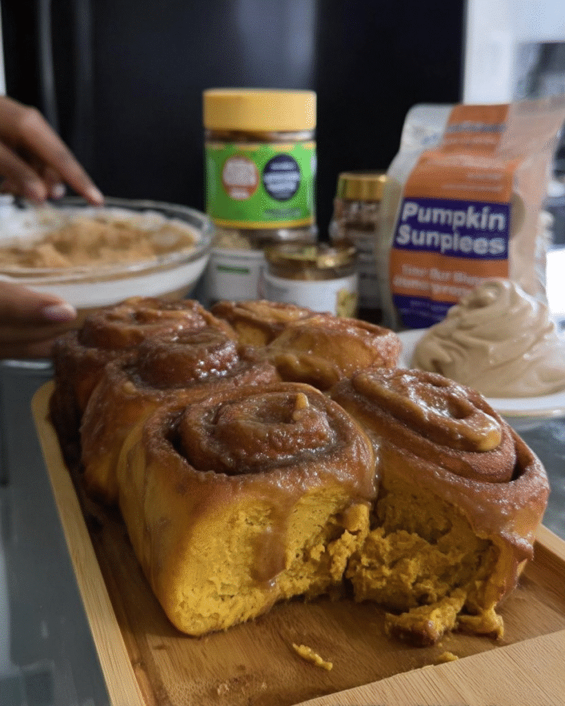 Pumpkin spice cinnamon rolls on fall-themed table with chai latte