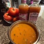 Tomato soup with fresh tomatoes in white bowl with basil