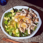 A colorful avocado and mango salad in a white bowl, garnished with cilantro.