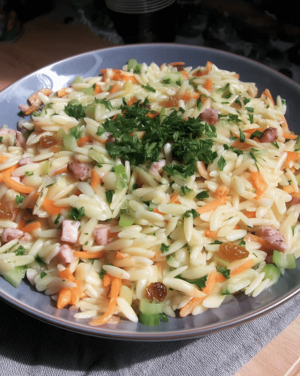 A close-up shot of a hand drizzling dressing over the Harvest Orzo Salad.