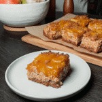Fudgy pumpkin brownies with a swirl of cream cheese filling on a wooden board.