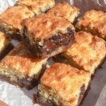 A batch of freshly baked pumpkin bars with chocolate chips on a baking sheet.