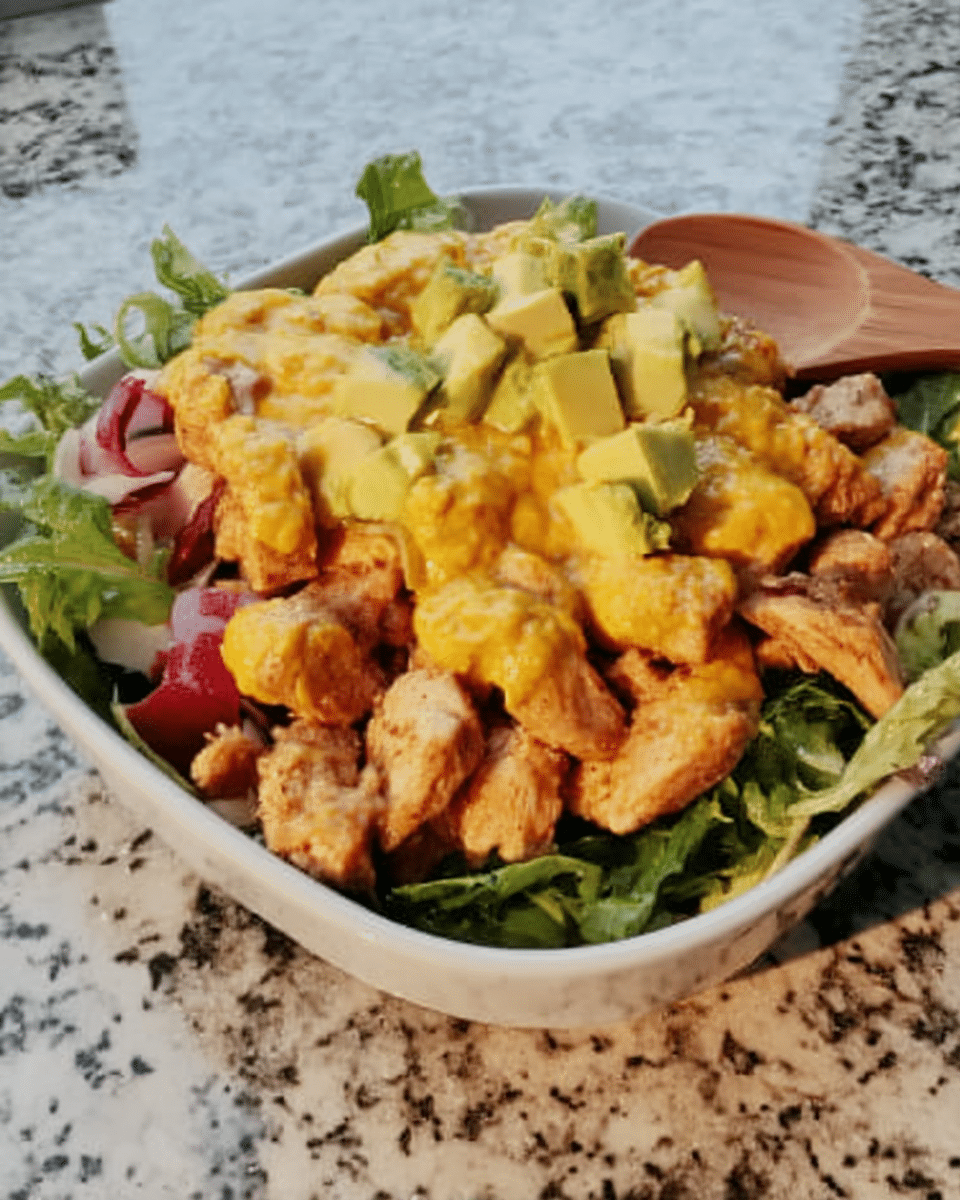 Avocado and mango salad served on a plate with grilled chicken.