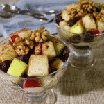 A close-up of a hand tossing the fall fruit salad with the cinnamon-orange dressing.