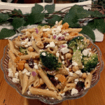 Close-up of hands tossing the pasta salad